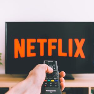 Hand holding remote to turn on Netflix