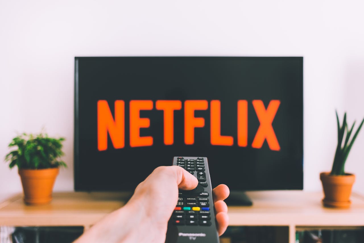 Hand holding remote to turn on Netflix